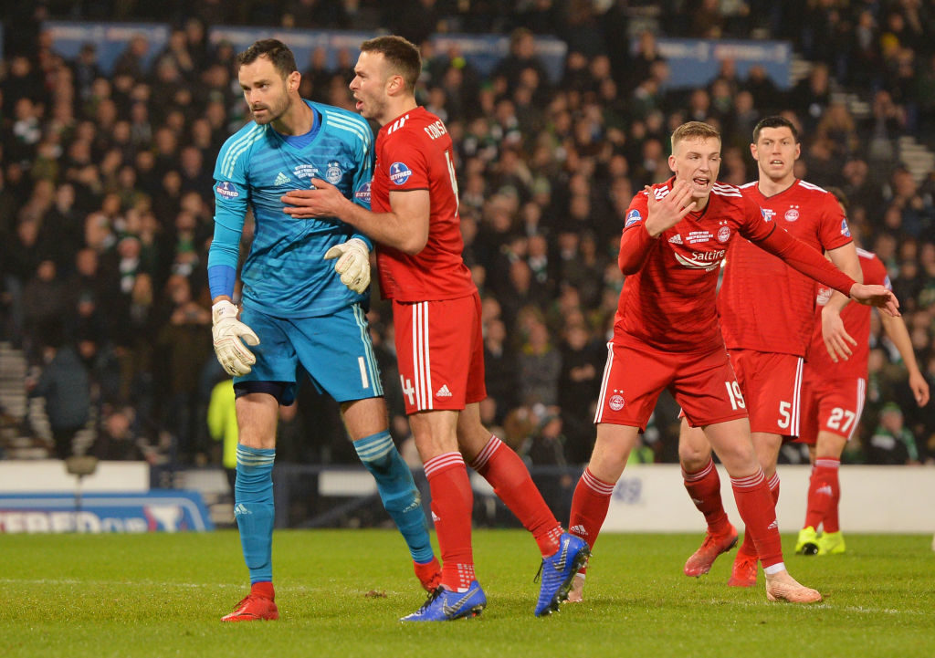 GLASGOW, SCOTLAND - DECEMBER 02: Joe Lewis of Aberdeen is congratulated by Andrew Considine as he saves a penalty from Scott Sinclair of Celtic during the Betfred Cup Final between Celtic and Aberdeen at Hampden Park on December 2, 2018 in Glasgow, Scotland.
