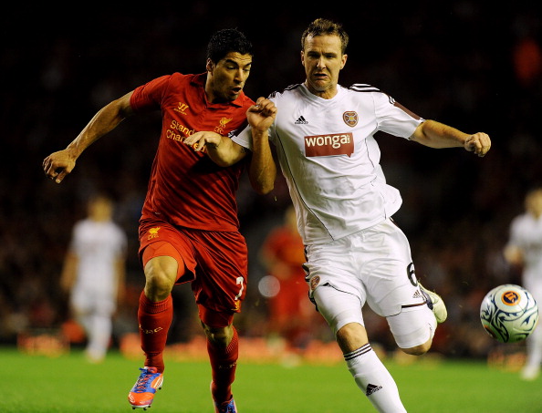 LIVERPOOL, ENGLAND - AUGUST 30: (THE SUN OUT, THE SUN ON SUNDAY OUT) Luis Suarez of Liverpool competes with Andy Webster of Hearts during the UEFA Europa League play-off round second leg match between Liverpool and Hearts at Anfield on August 30, 2012 in Liverpool, England. 